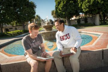 Two students sitting by the swimming pool 
