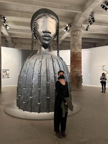 Two people standing in an art museum near a large sculpture.