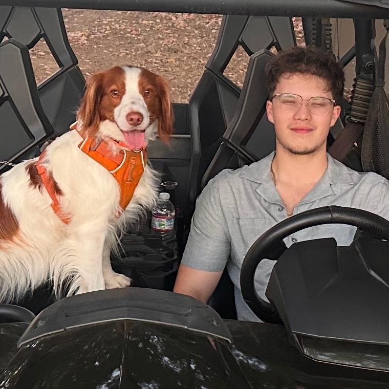 Tyler Pineda at the wheel with his dog in passenger seat.