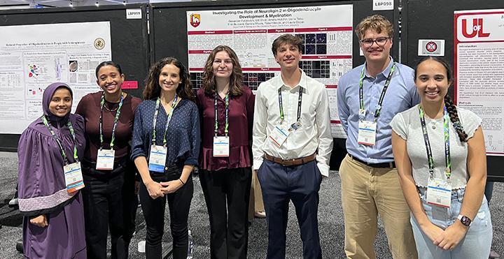 4 female students and 2 male students with their SCU professor at a conference
