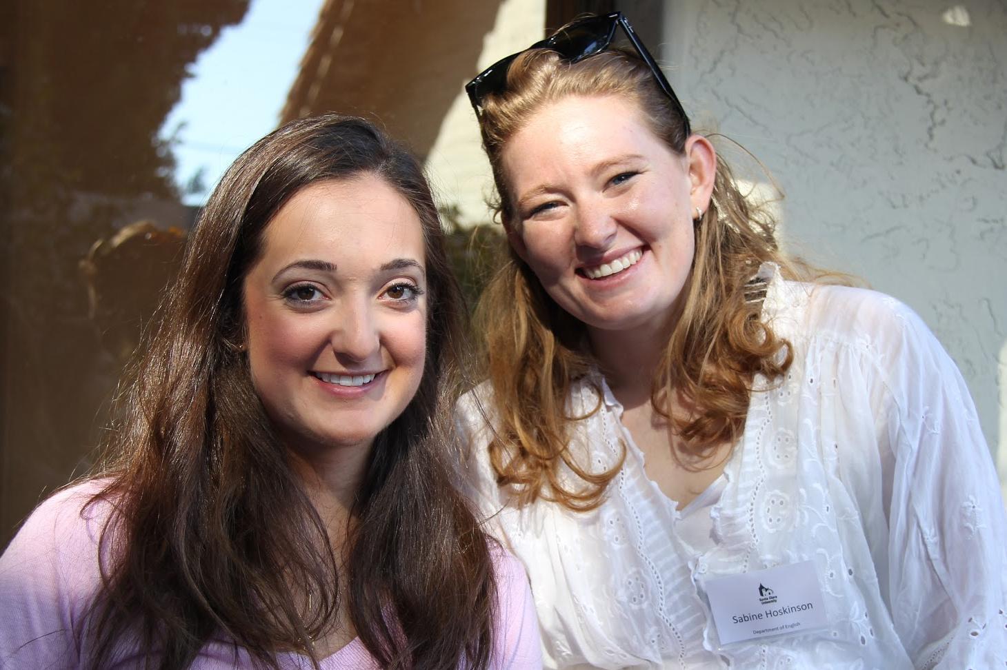 Two people smiling at an event with name tags. 