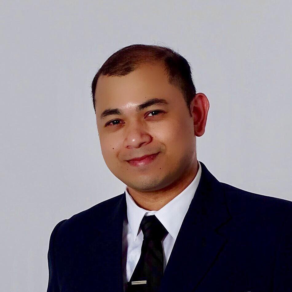 A person in a suit against a plain background.