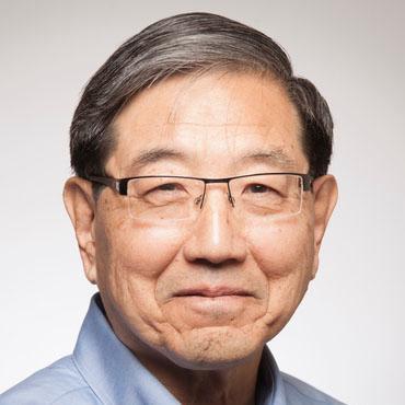 Man wearing glasses and a blue shirt against a light gray background.
