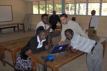 A group of people working on laptops in a classroom.
