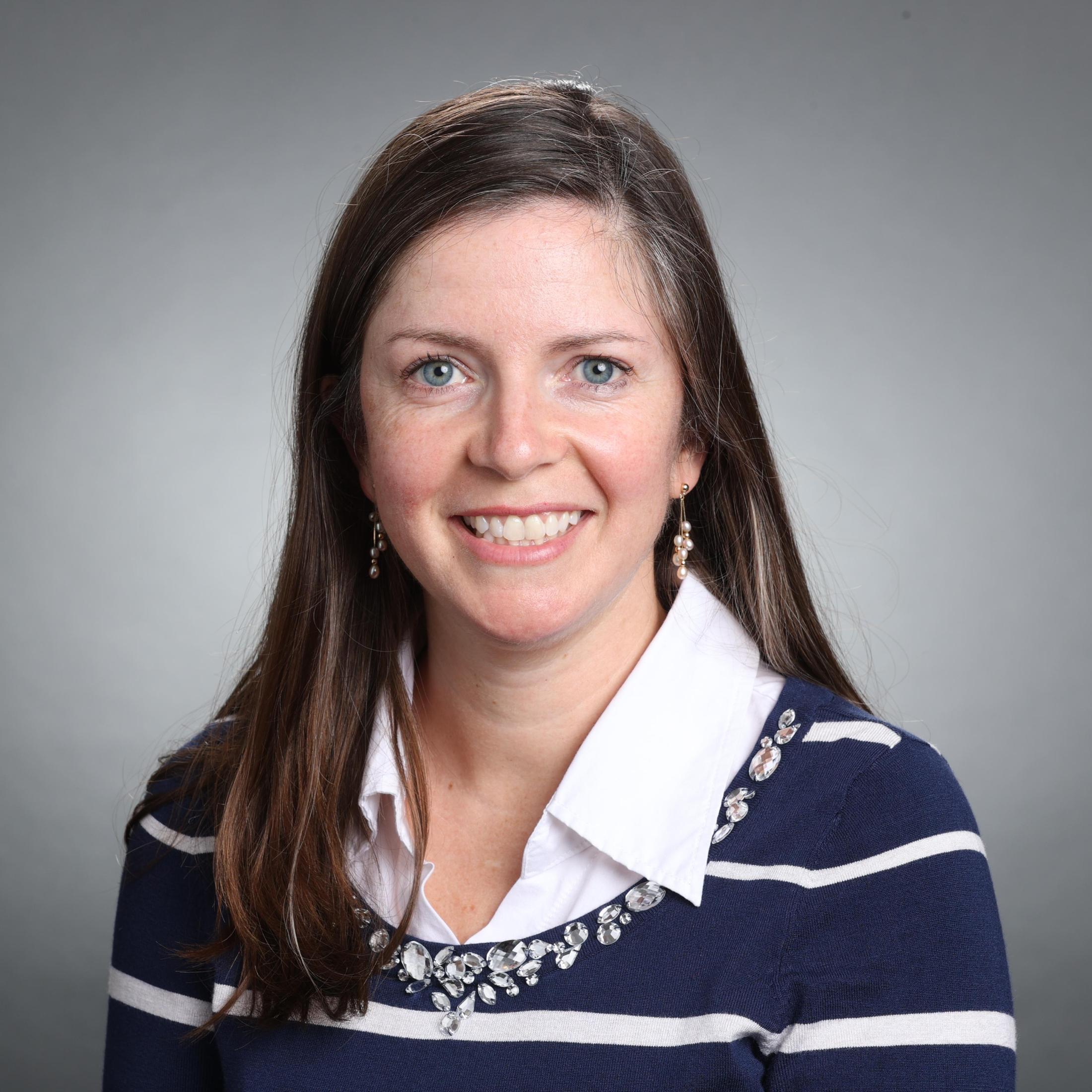 A person smiling in a striped sweater.