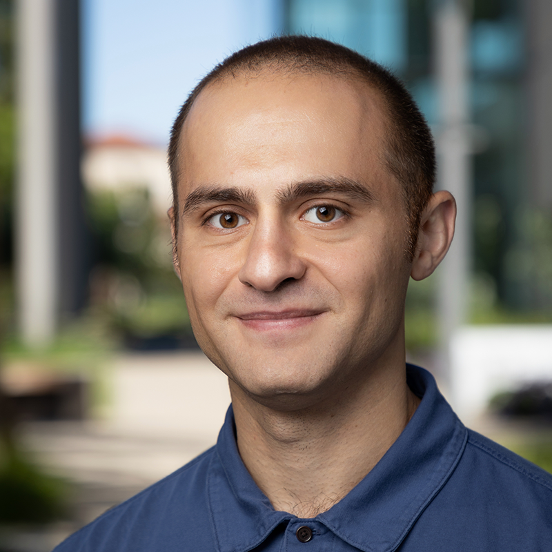 A person wearing a blue shirt, standing outdoors.