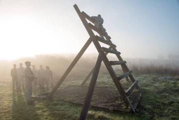 Foggy field with a large wooden A-frame structure in the morning sun.