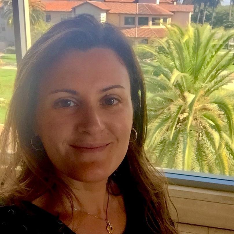 A person standing by a window with palm trees outside.