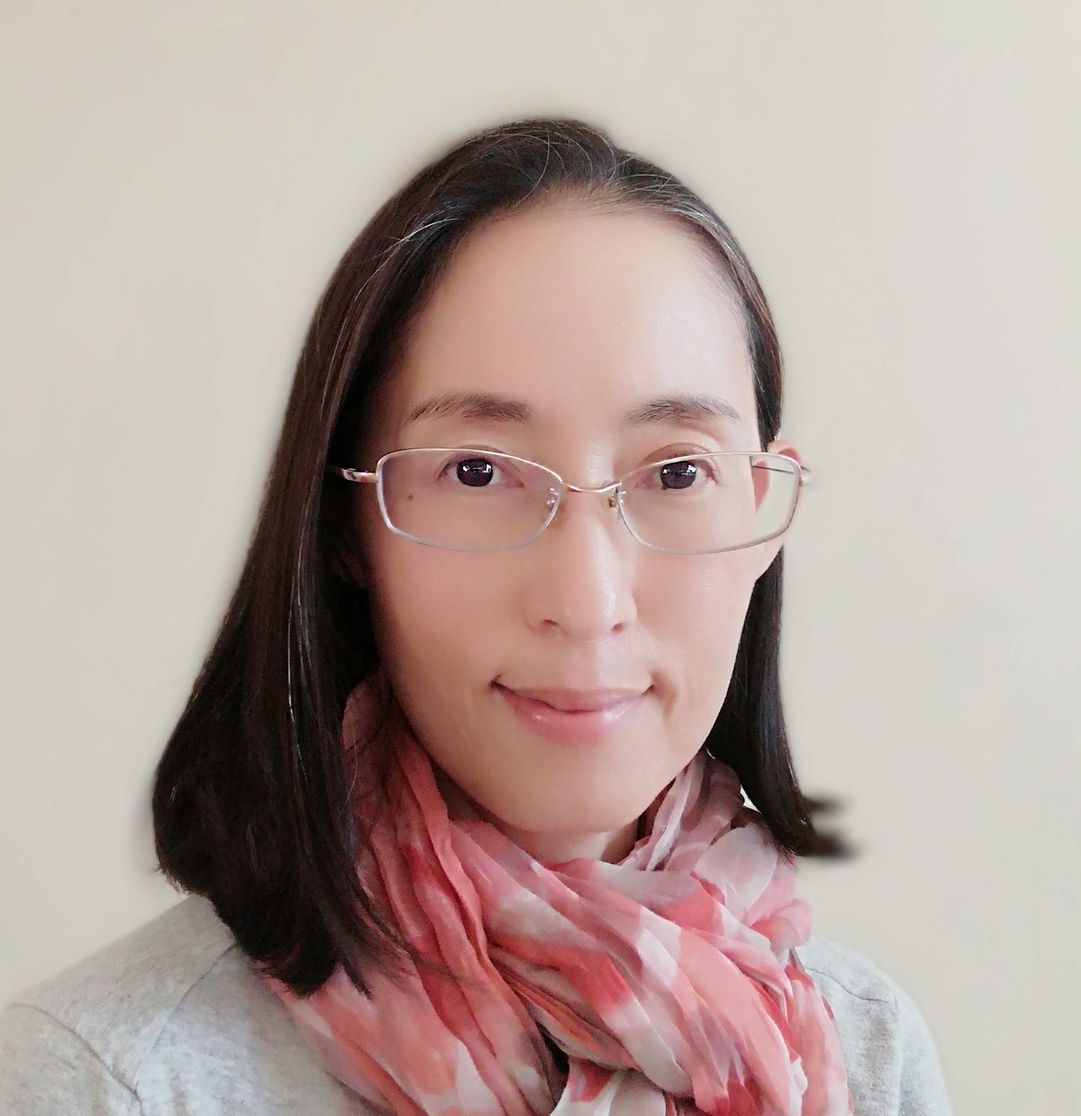 A person wearing glasses and a red patterned scarf, with a neutral background.