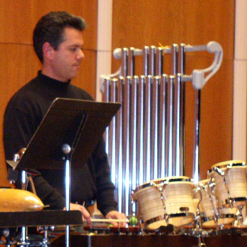 A person playing orchestral percussion instruments on stage.