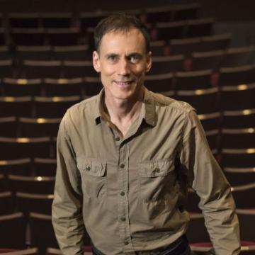 A man standing in front of wooden shelves.