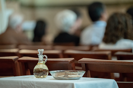 Small bottle and plate on a table, people blurred in the background.