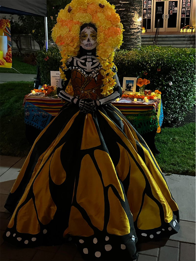 Woman in yellow and black Day of the dead dress with a yellow and orange headdress