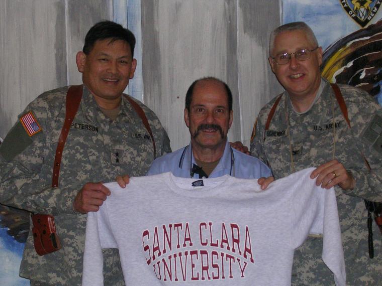 Three individuals, one holding a shirt, at the American Embassy in Baghdad. 