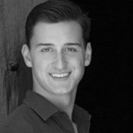 A person smiling in a black-and-white photo.