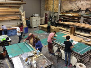 A group of people working in a workshop with large tables. 