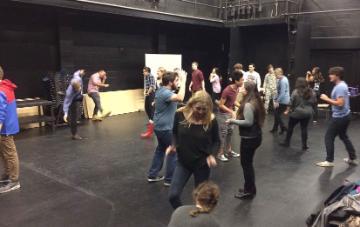 People participating in an improv class in a large room. 