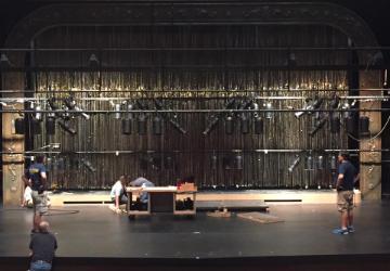 A dimly lit stage with hanging lights and equipment. 