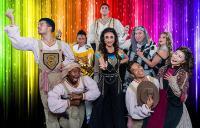 Joseph and the Amazing Technicolor Dreamcoat cast in front of a rainbow shimmer backdrop