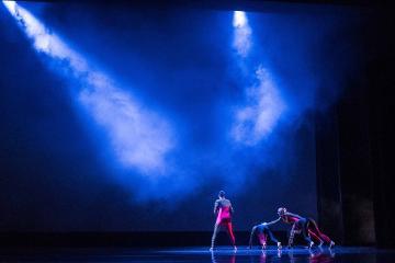 Performers on stage with blue lighting effects and spotlight.