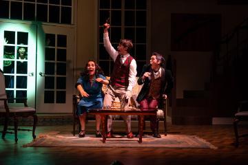 3 people dressed in 1930s costumes looking surprised by a woman outside their patio door