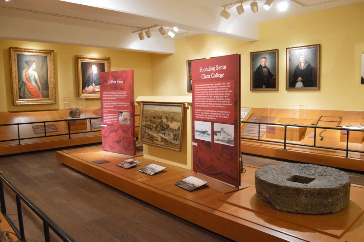 Exhibition room with display panels, portraits, and historical artifacts.