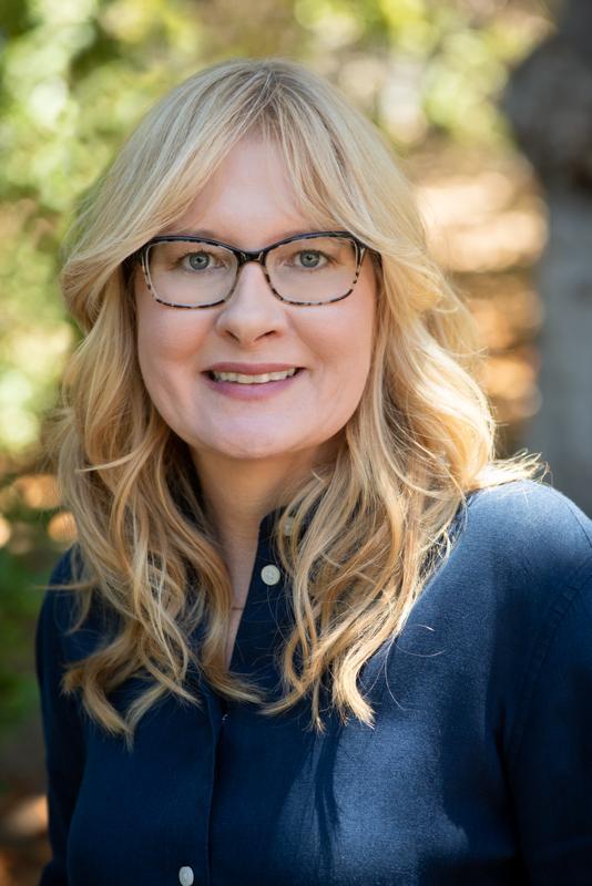 A woman with glasses smiling