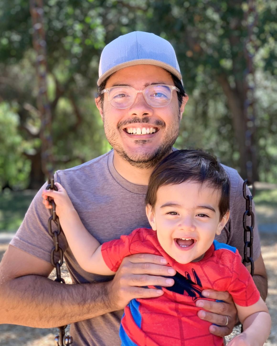 A man holding a smiling child outdoors. image link to story
