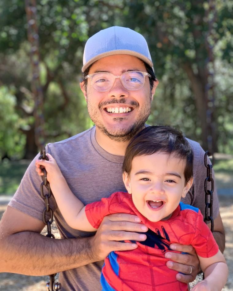 A man holding a smiling child outdoors. image link to story