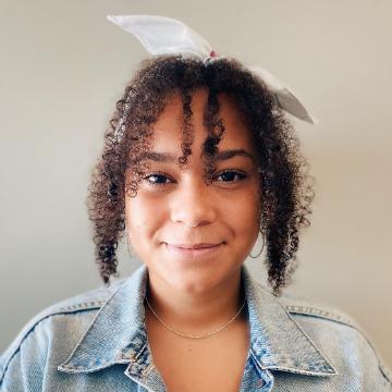 A person smiling, wearing a denim jacket with a white background.