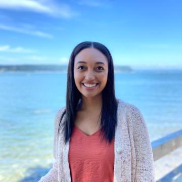 Woman smiling with an ocean background, titled 