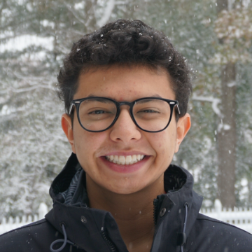 A person smiling with snow falling around them.