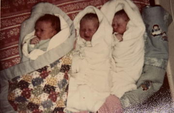 Lowrey Infants: Triplets Rebecca, Jessica, and Rachael laying side by side swaddled in baby blankets. Photos by 