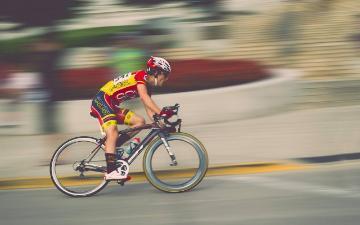 Cyclist on racing bike in-motion with blurred background. Image by Pexels from Pixabay.