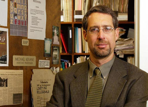 A man in an office with filled shelves.