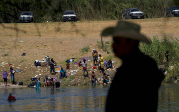 Man standing in front of a body of water with people in the background