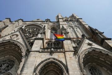 A rainbow flag is hanging on the side of a church building. Photo by Bertrand Colombo on Unsplash.