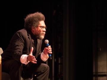 A person speaking into a microphone on a stage.