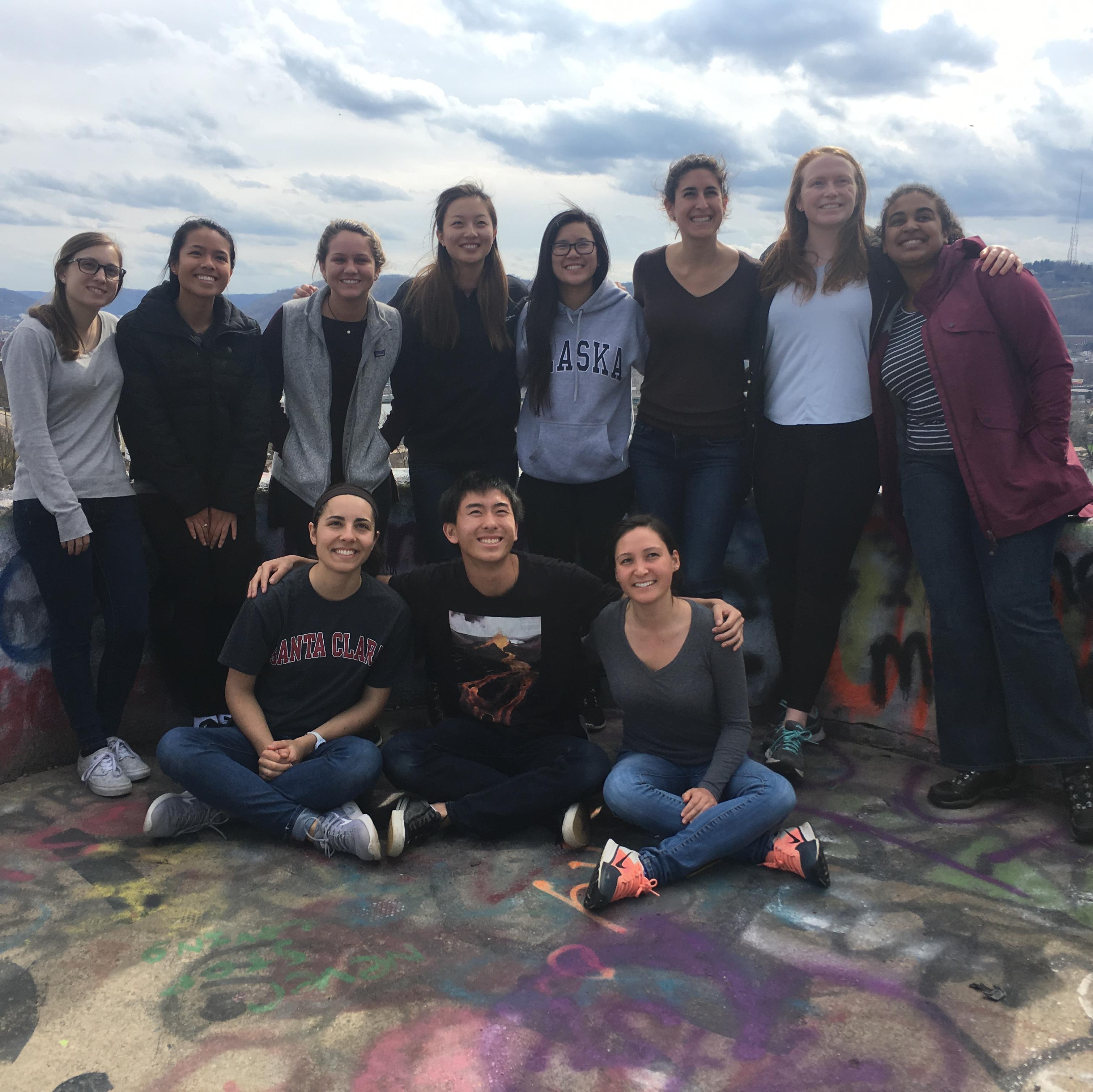 Alt text: Group of people posing outdoors with a scenic, mountainous background.