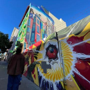 Mural in the Tenderloin with back of student looking up