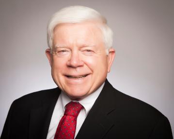 Man in a suit and red tie posing for a portrait.
