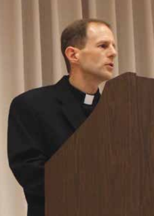 A person speaking at a podium during a lecture.