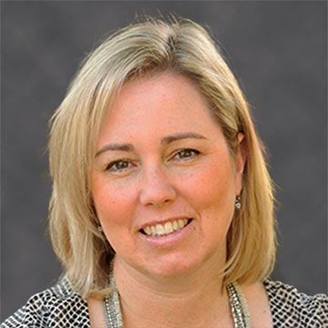 A person smiling against a dark grey background.