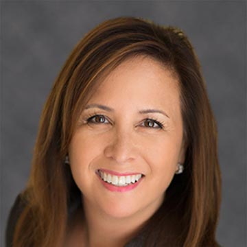 A person smiling with a gray background.