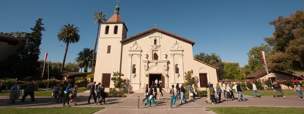 Mission-style building at Santa Clara University with a garden and palm trees. image link to story
