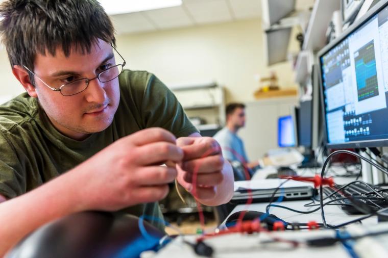 A student working on an electronic project in a lab.