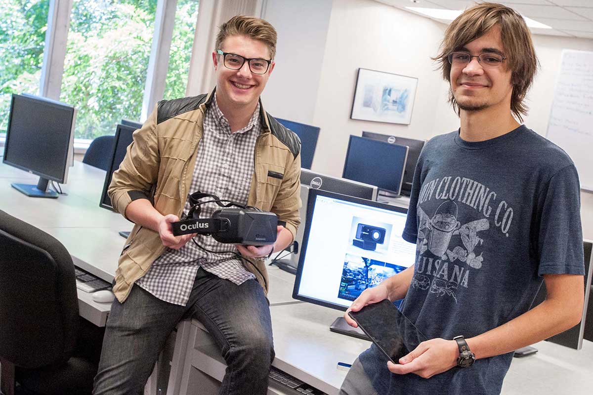 Two people holding an Oculus Rift in an office setting.