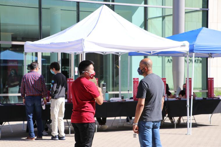 People are gathered around booths and tents outdoors.