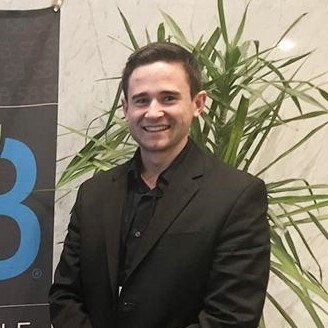 A person standing in front of a plant and a banner.