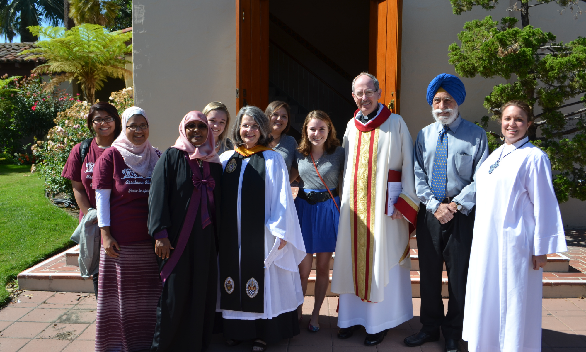 A group of people in various religious garments standing outside a building.